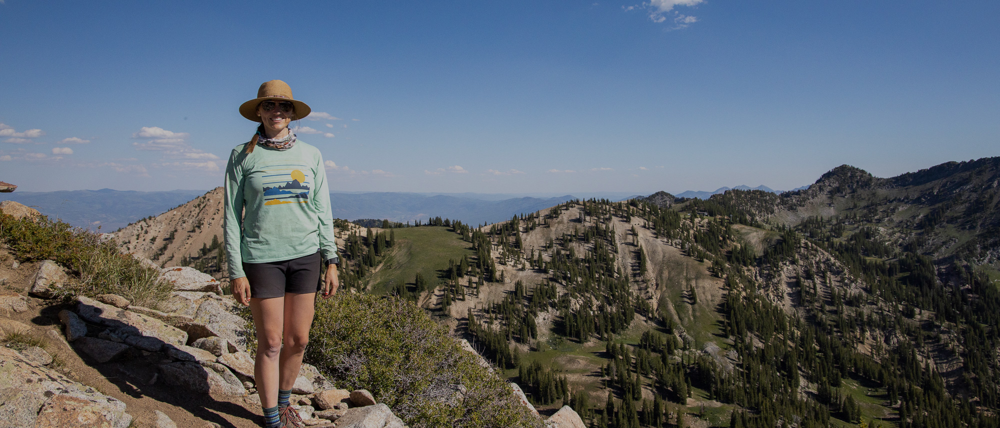 Hiker posing for a picture on the top of a mountain wearing Oboz hiking boots