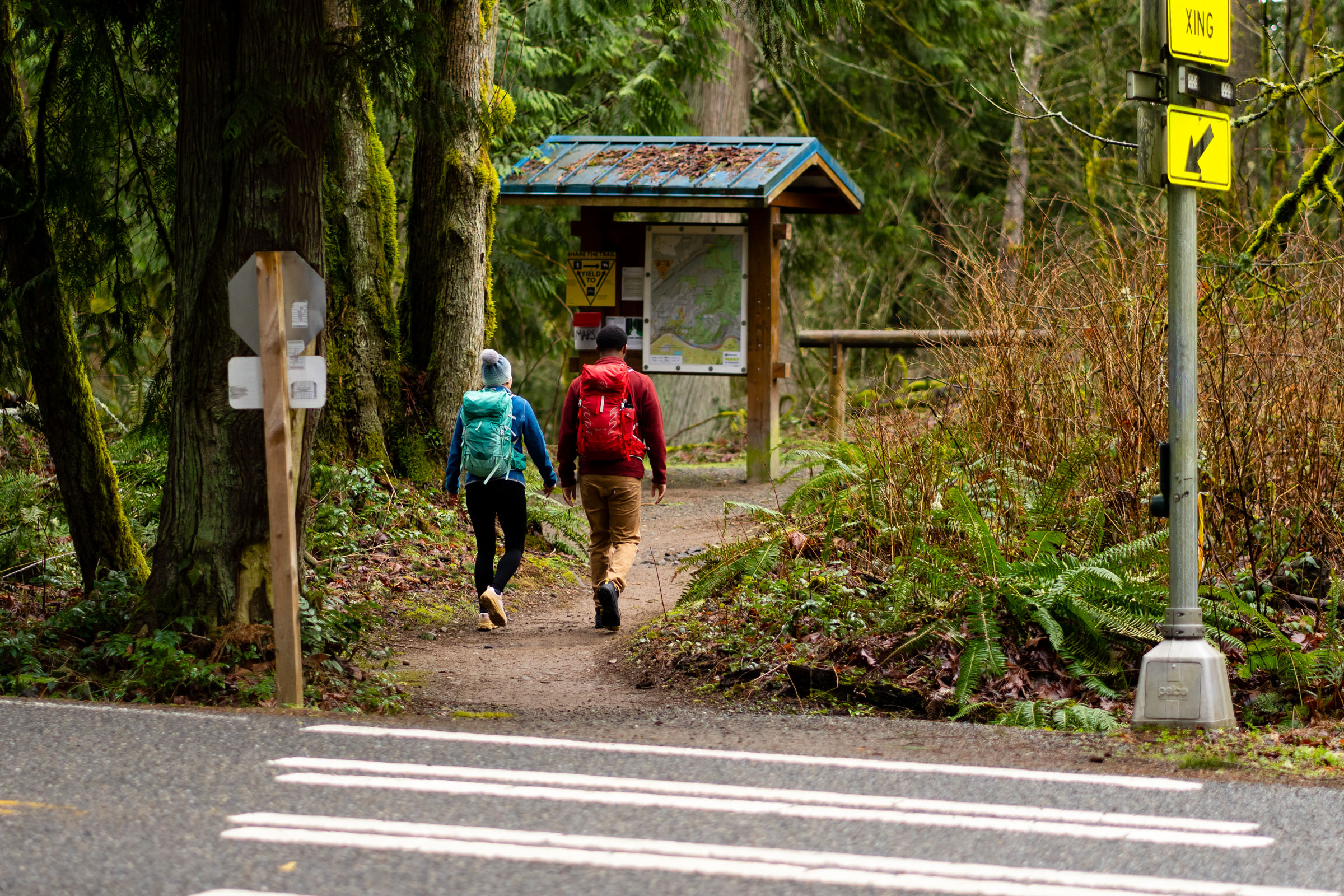 Two people starting a hike at a trailhead in their Oboz hiking shoes.