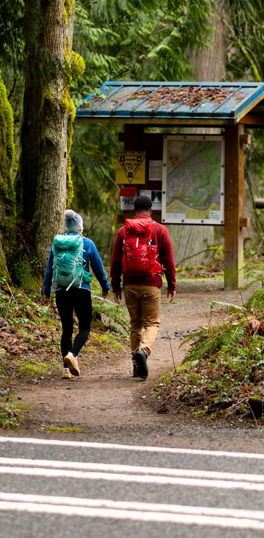 Two people starting a hike at a trailhead in their Oboz hiking shoes.