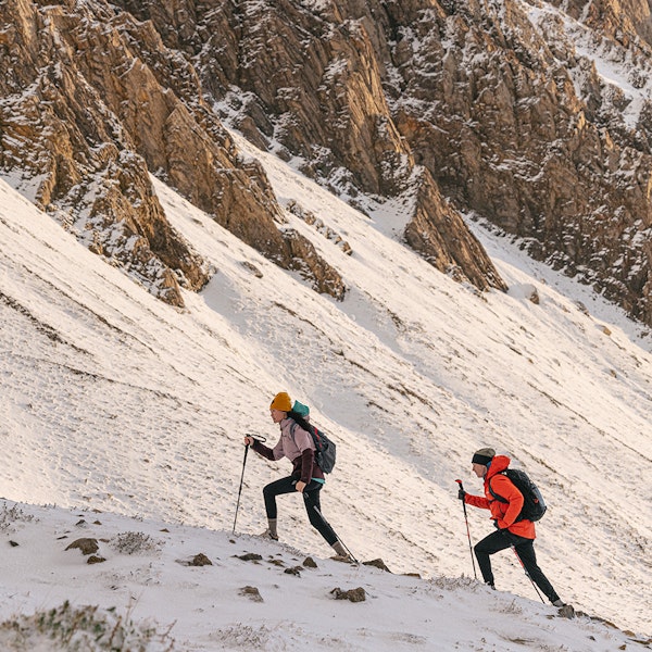 Two people hiking in the snow in the Katabatic Mid Waterproof boots.