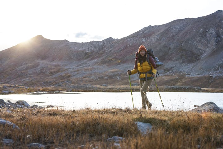 Woman hiking in Oboz hiking boots past an alpine lake in the fall.