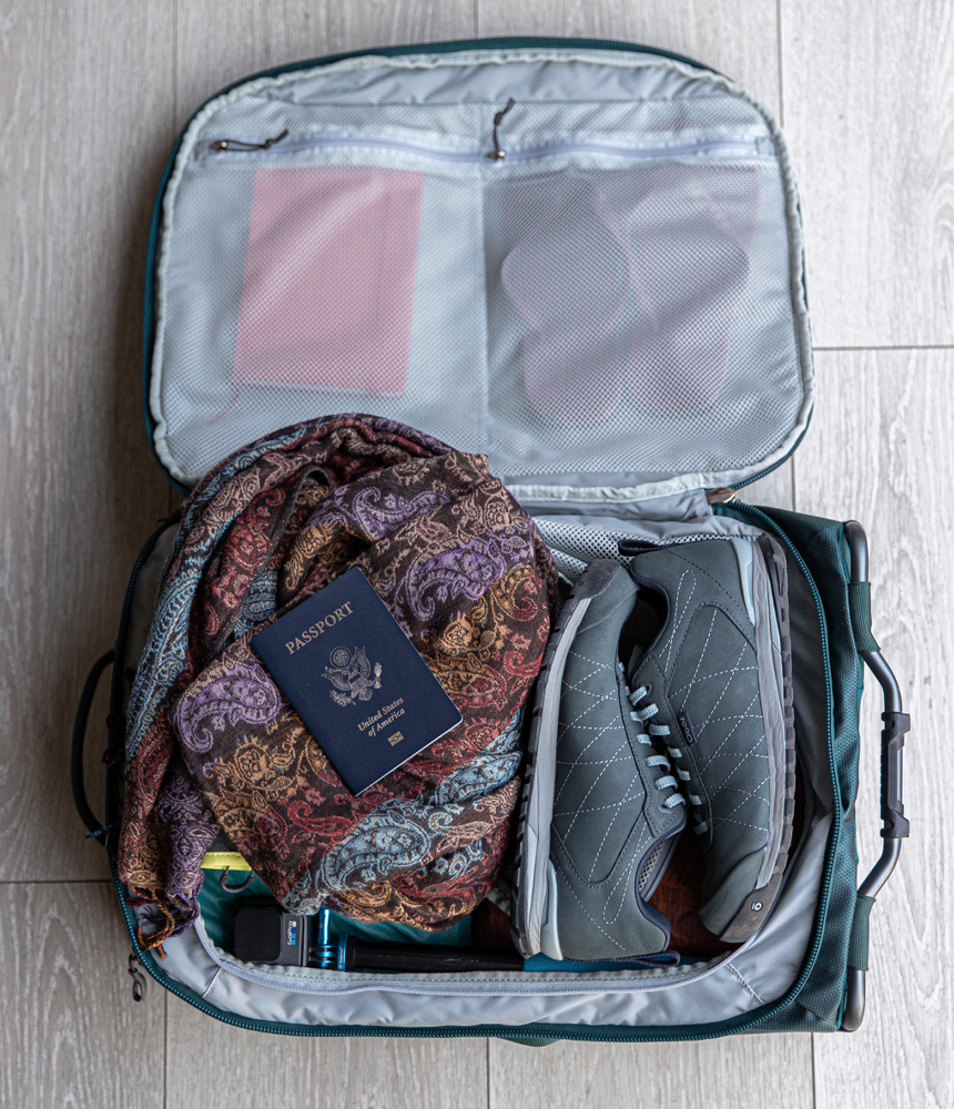 Suitcase zipped open with the Women's Bozeman Low shoes, a scarf and a passport