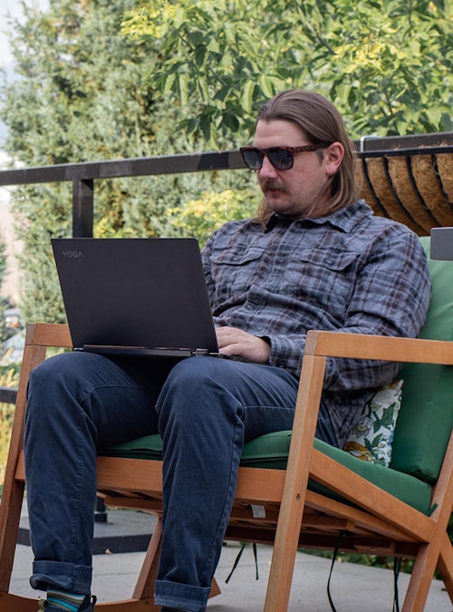 A man works outside on a computer in the Whakatā Collection
