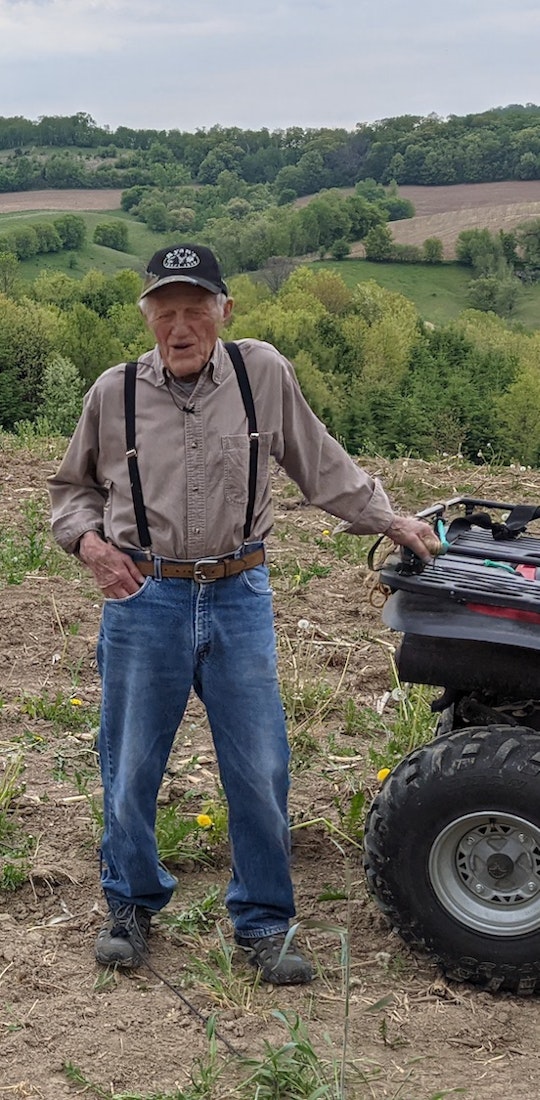 A farmer out in the field with his ATV four wheeler.