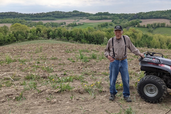 A farmer out in the field with his ATV four wheeler.