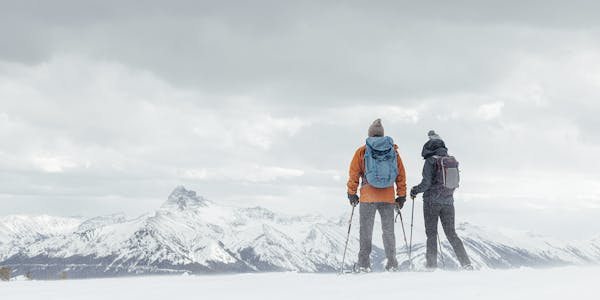 Two hikers enjoying a snowy mountain view while on a winter hike.