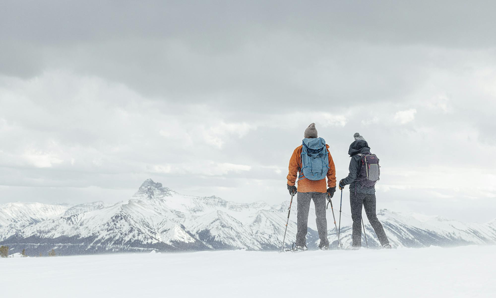 Two people on a snowy ridgeline wearing Oboz Bangtail insulated hiking boots.