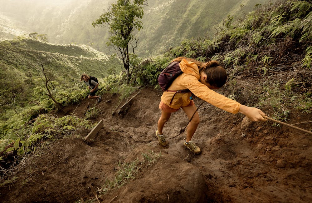Couple hiking up a muddy trail in Hawaii in Oboz Cottonwood Low Waterproof hiking shoes.