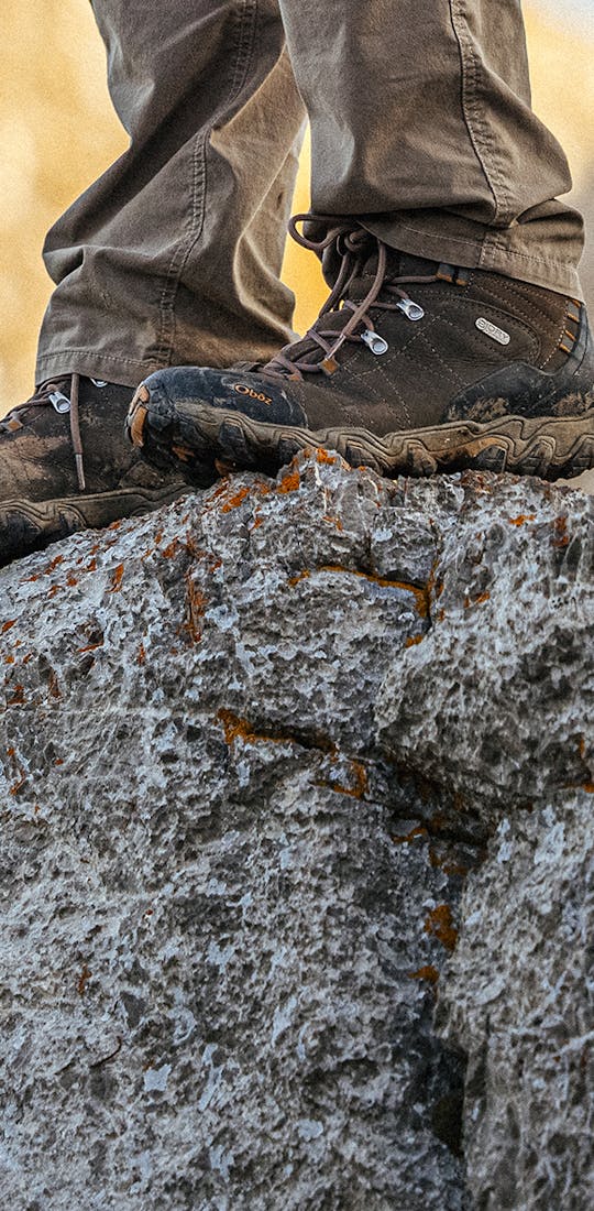 Hiker in Mens Oboz Bridger Mids on top of a rocky cliff while hiking.