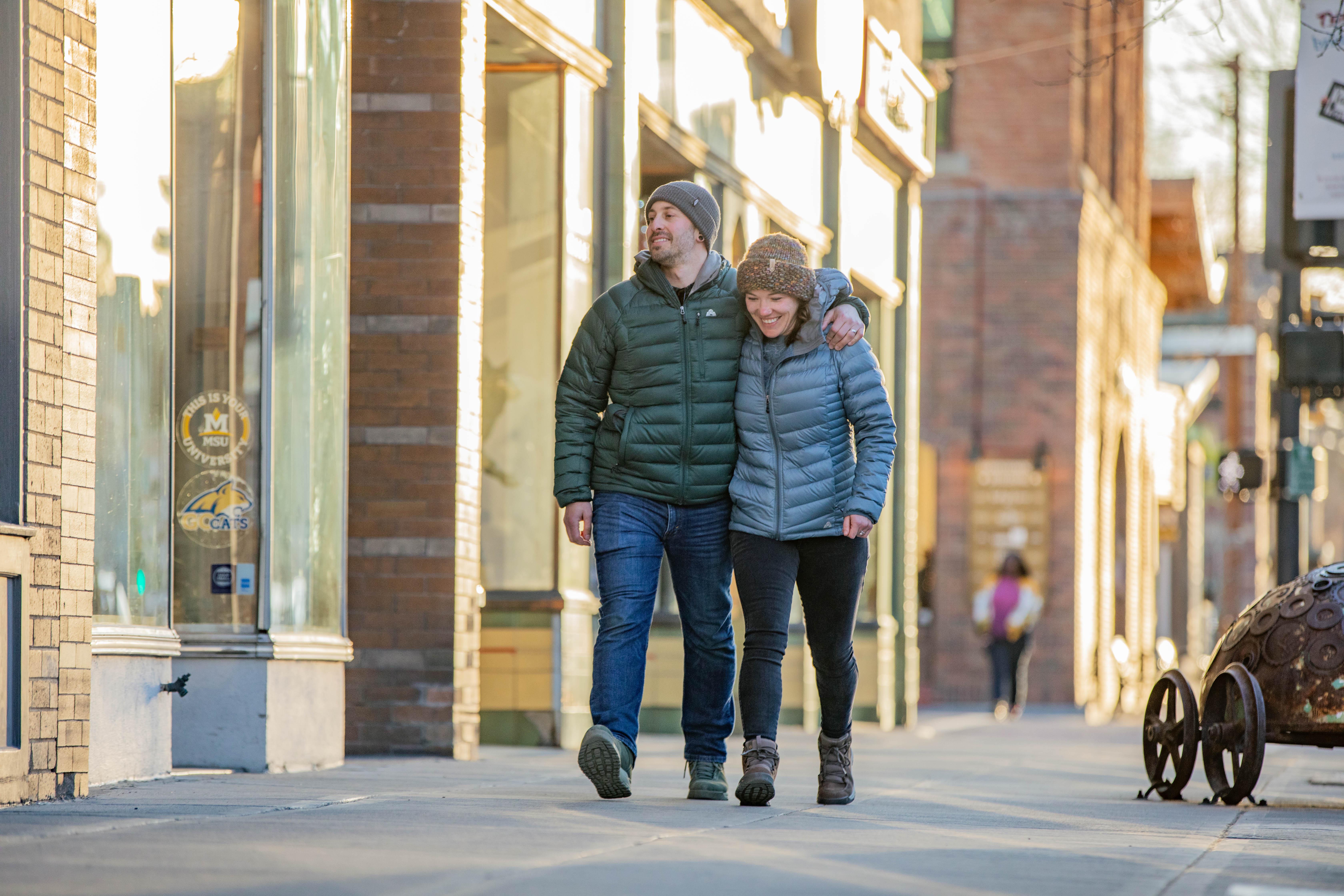 A couple walks downtown Bozeman while staying warm in puffy jackets and Oboz insulated boots.