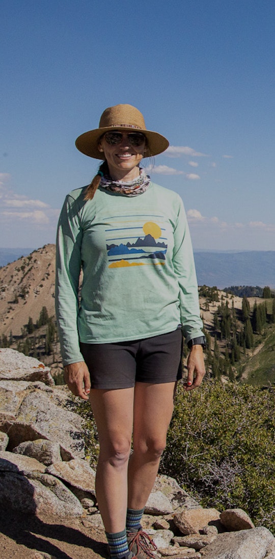 Hiker posing for a picture on the top of a mountain wearing Oboz hiking boots