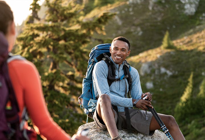 Man sitting on a rock while on backpacking trail.
