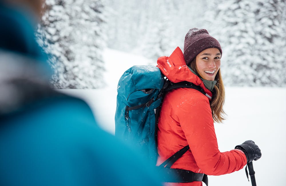 Woman smiling while on a snowshoeing trip in the woods.