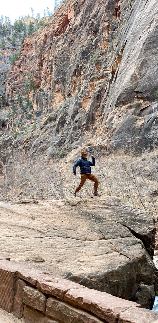 A person striking a pose on top of a boulder in the Bridger Mids Rio Red