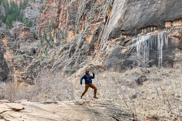 A person striking a pose on top of a boulder in the Bridger Mids Rio Red