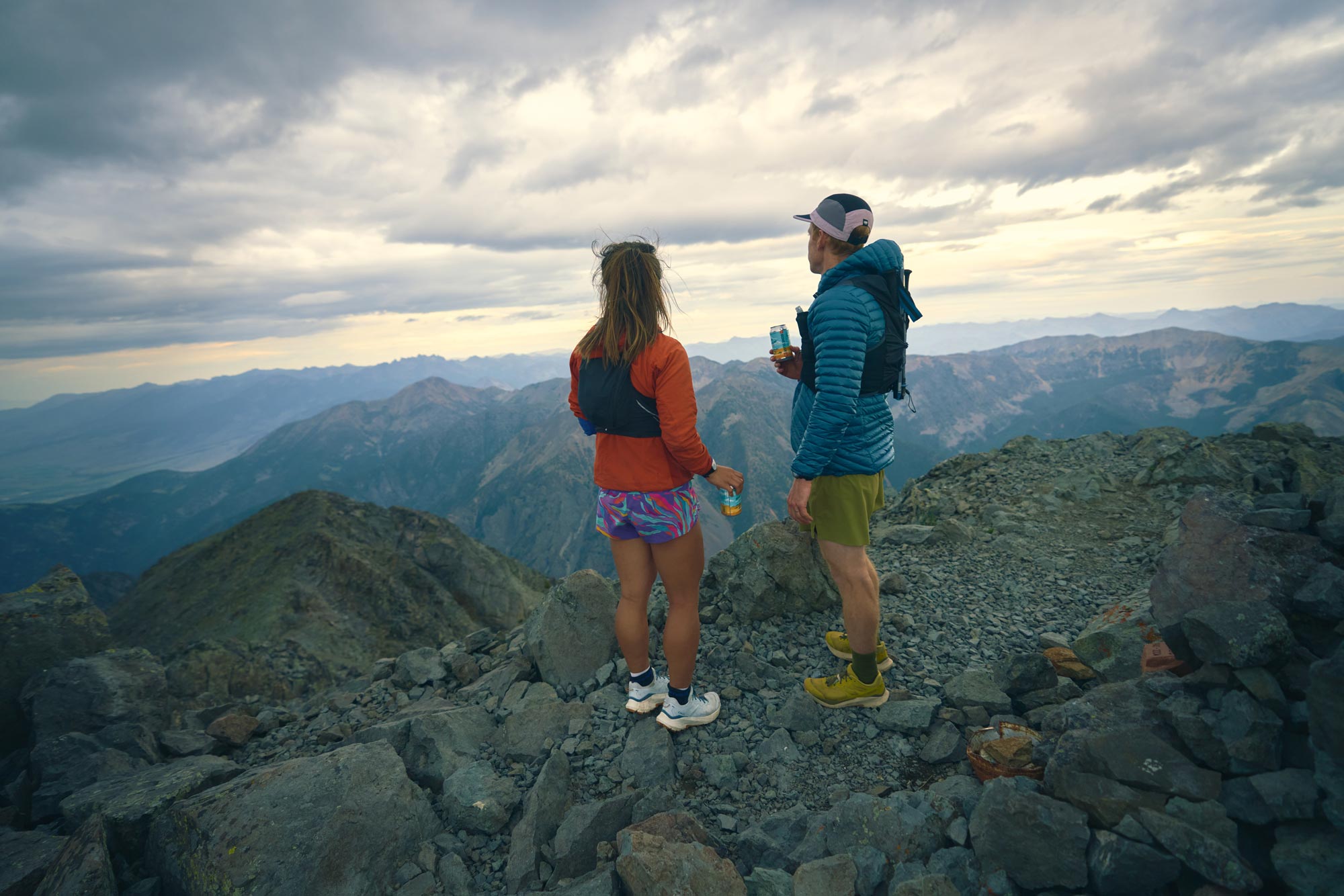 Two hikers gazing upon a mountain landscape after scaling a peak.