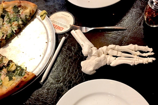 Human foot skeleton model and pizza staged for an informative Oboz article.