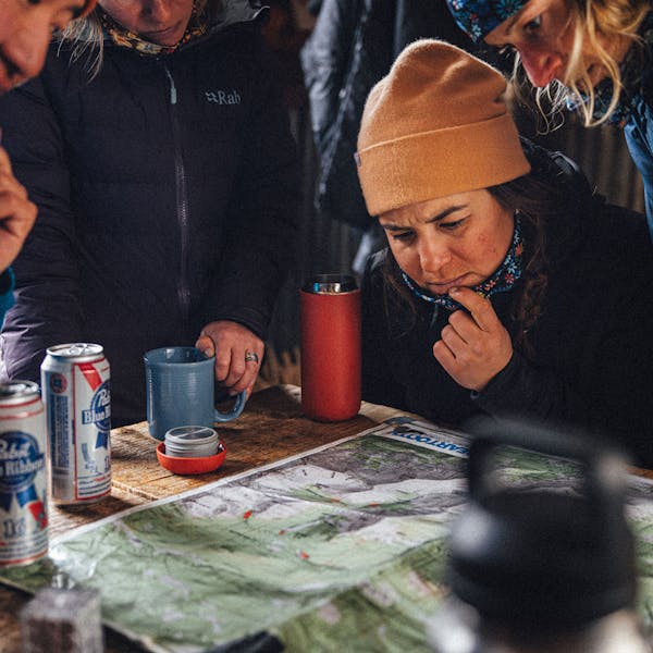 Planning the day over a map in the Oboz and Skida Whakatā Puffy slipper shoe.