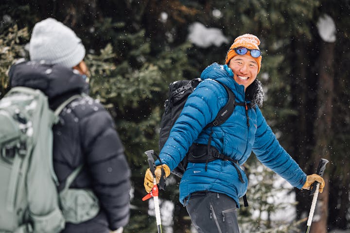 Snowshoer hiking through a snow covered forest in Oboz winter boots.