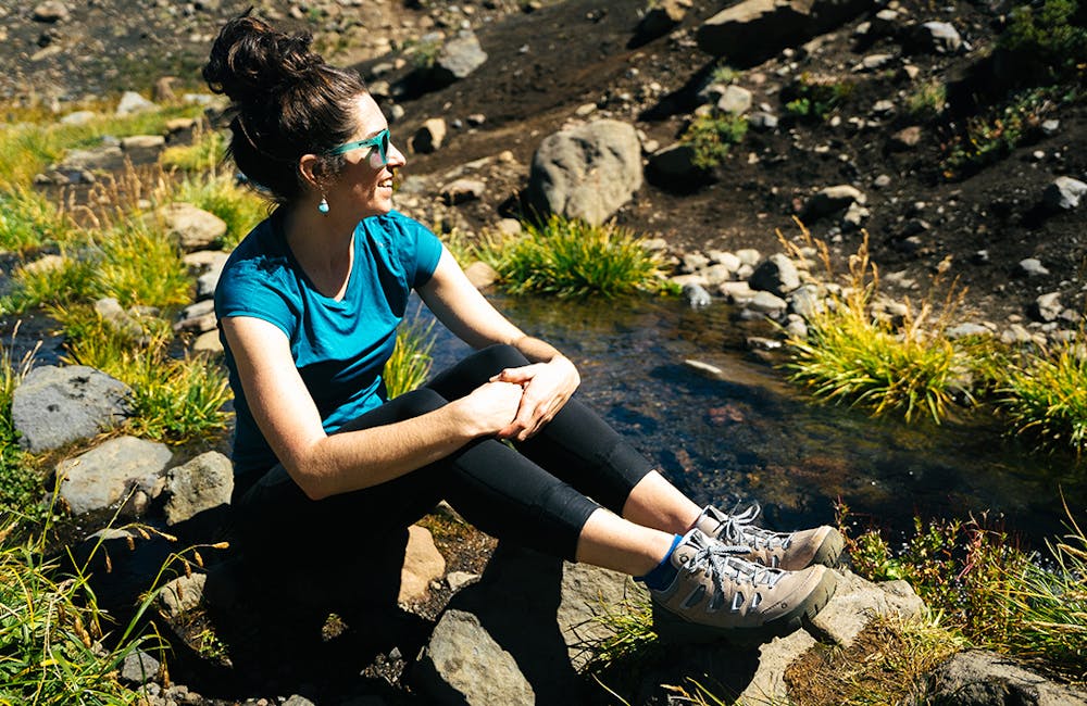 Oboz Ambassador Jackie Nourse smiling while on a hike near a creek bed.