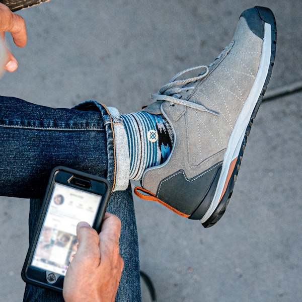 Man scrolling Instagram in the Oboz Bozeman Low Leather casual shoes.