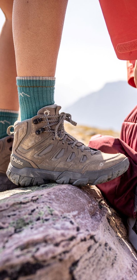 Oboz Sawtooth X Mid height hiking boot next to backpacking backpack. 