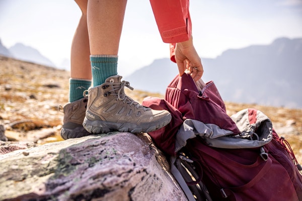 Oboz Sawtooth X Mid height hiking boot next to backpacking backpack. 