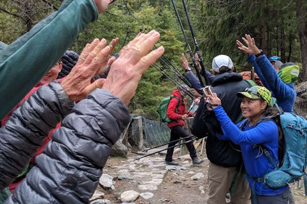 Group of hikers cheering one another on along the trail with their trekking sticks.