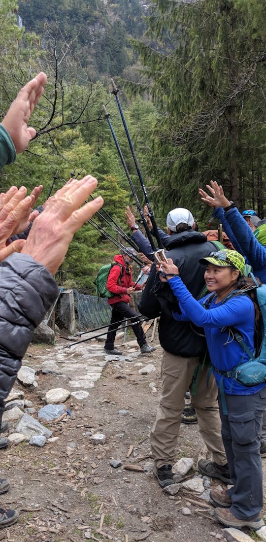 Group of hikers cheering one another on along the trail with their trekking sticks.