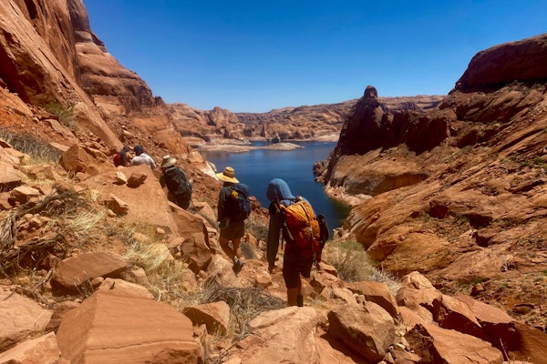 5 hikers walk towards a lake in David Canyon during the heat of the summer in their Oboz hiking boots