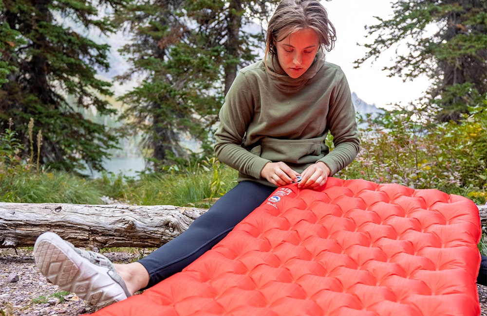 Hiker inflating a camping pad while wearing the Oboz Whakata Trail.