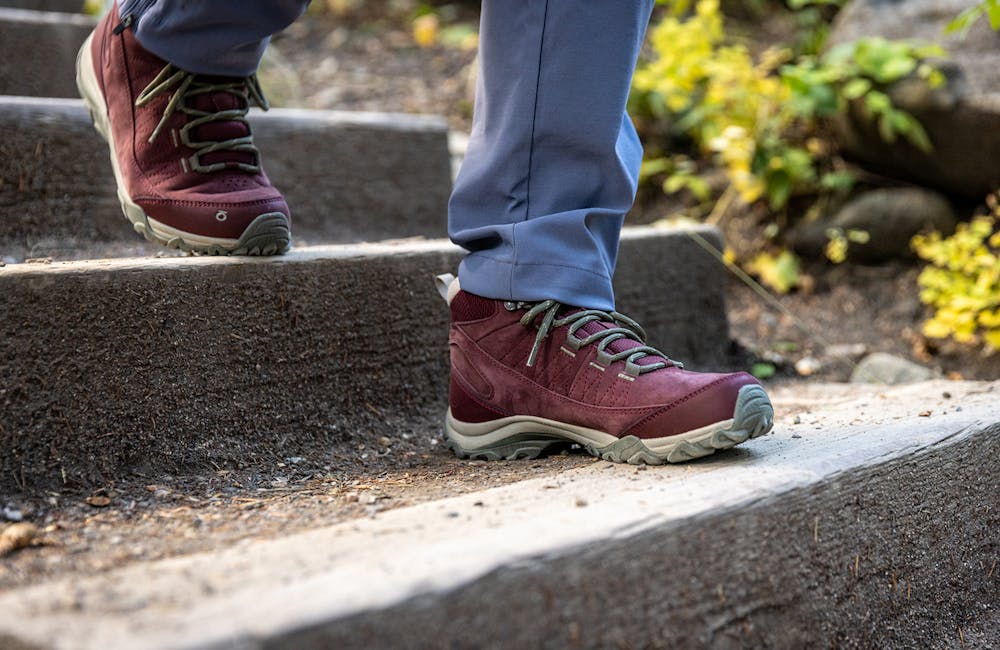 The Oboz Ousel Mid hiking boot walking down concrete stairs.