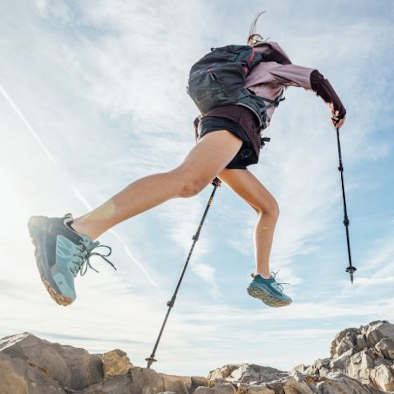 Two runners in Oboz Katabatic trail shoes leap across rocky terrain 