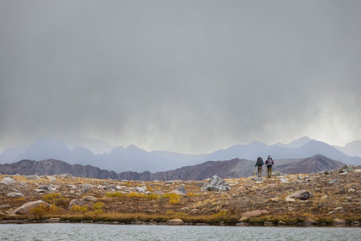 Two hikers wearing Oboz Bridger Mid hiking boots heading into a storm in the high Colorado alpine.