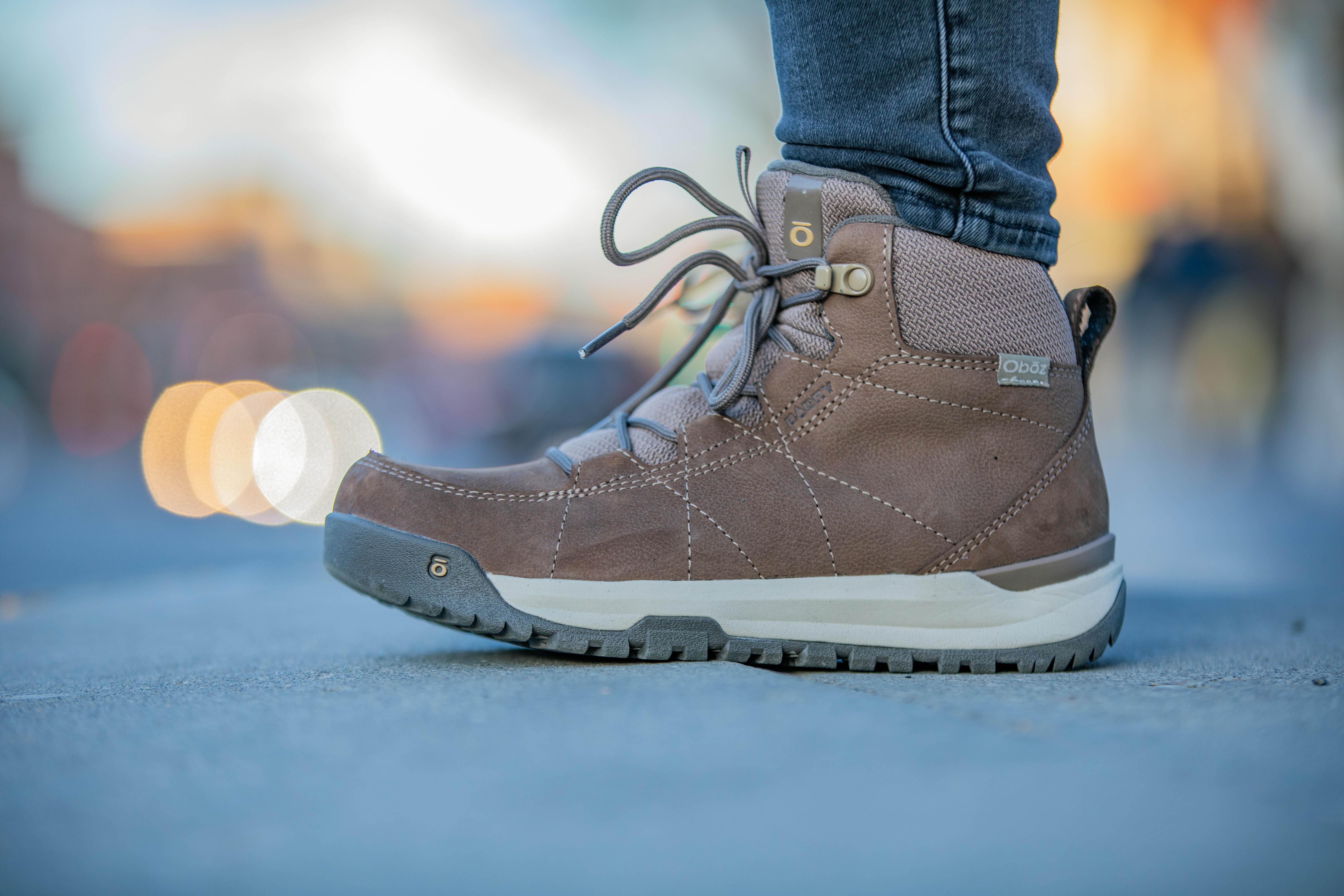 A woman wears a pair of Oboz Cedar winter boots on a paved sidewalk.