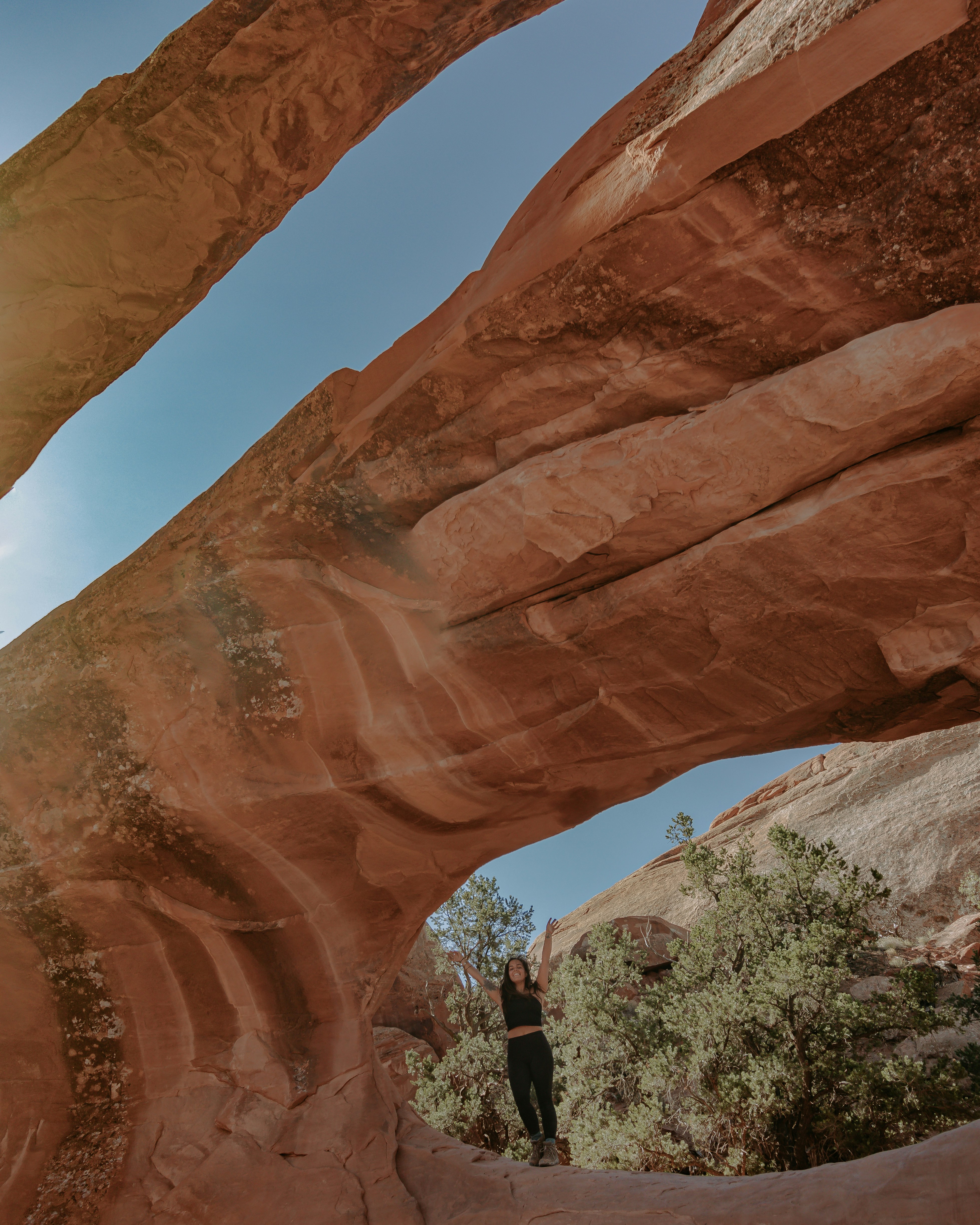 Lindsay Kagalis under an arch formation on Núu-agha-tʉvʉ-pʉ̱ (Ute) Indigenous lands