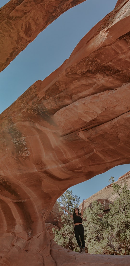 Lindsay Kagalis under an arch on Núu-agha-tʉvʉ-pʉ̱ (Ute) Indigenous lands