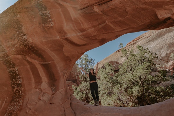 Lindsay Kagalis under an arch on Núu-agha-tʉvʉ-pʉ̱ (Ute) Indigenous lands