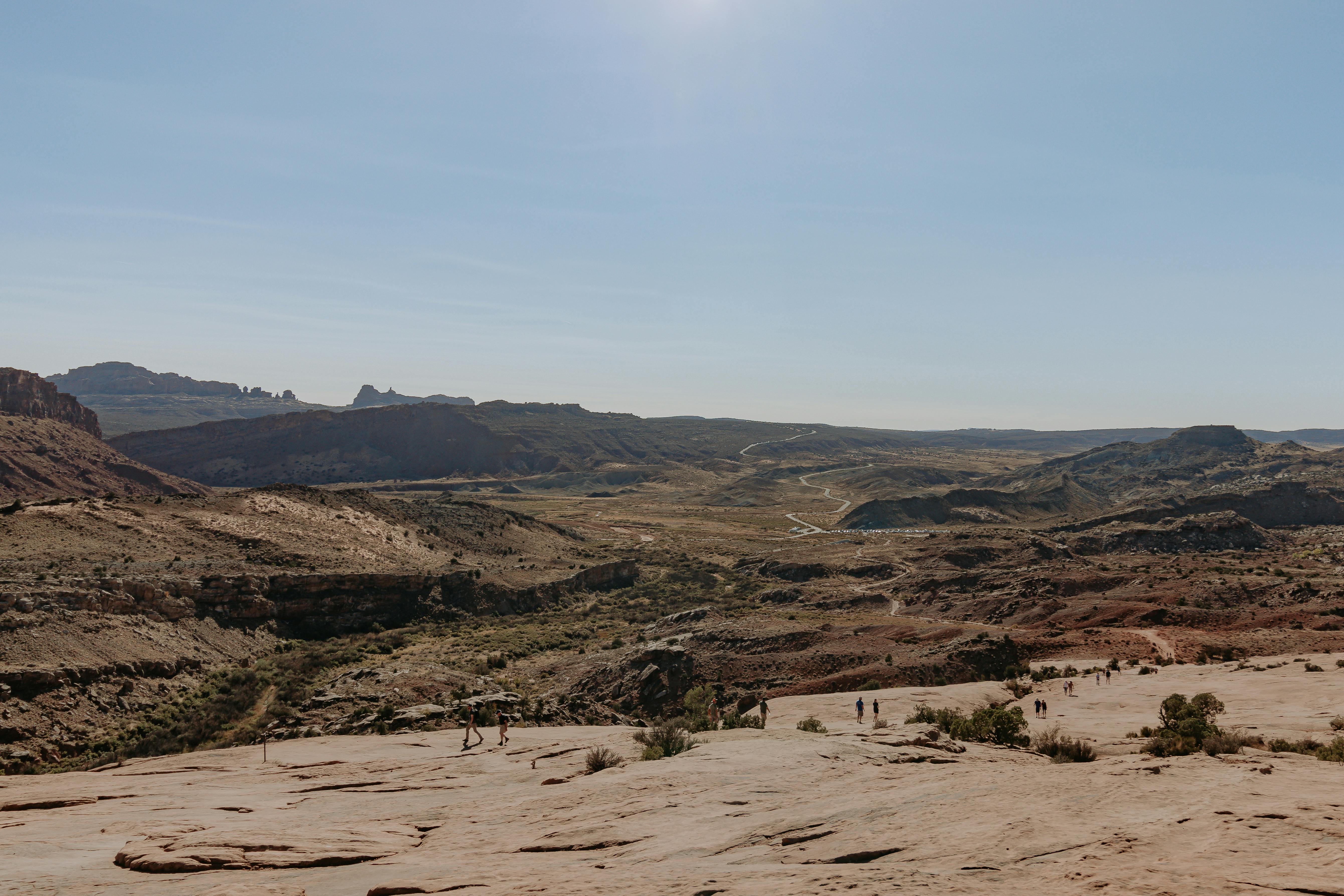 Groups of people hiking to Delicate Arch.