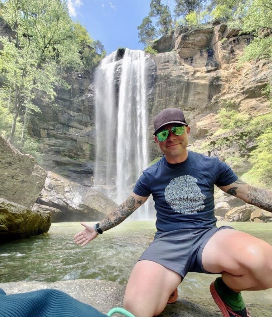 Hiker posed in front a waterfall during the summer