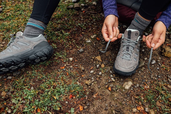 A hiker lacing up the Sawtooth X Low hiking shoes on the trail.