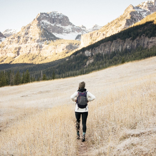 Woman hiking in the Oboz Sawtooth II Low in a mountain meadow.