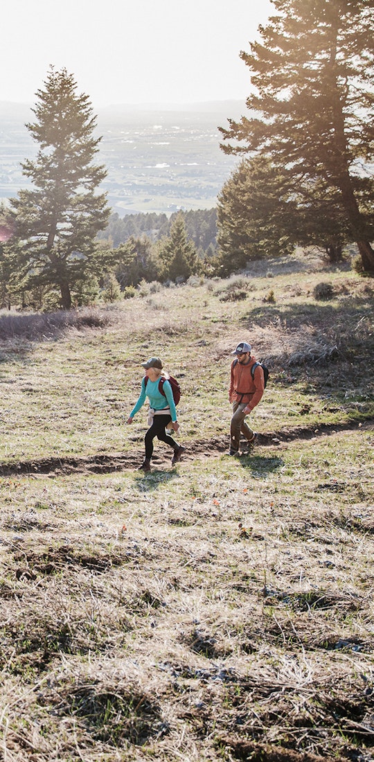 Two hikers trekking through the mountains on a trail in Montana.