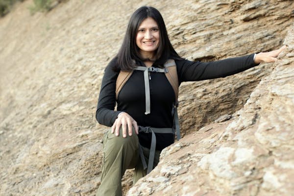 Karla Amador standing along a rock wall wearing Oboz hiking shoes