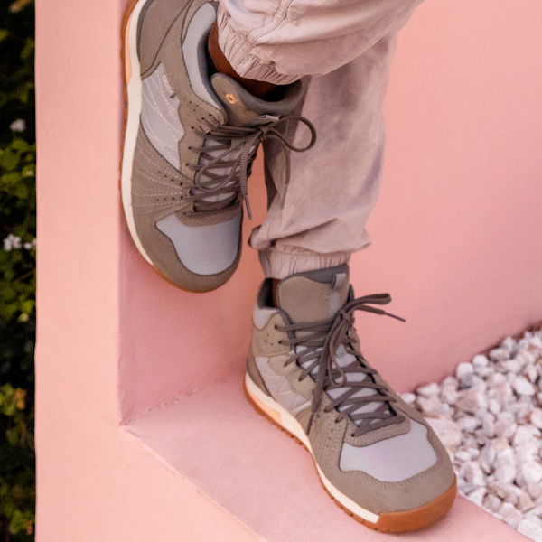 A person relaxing on a ledge wearing Oboz Women's Bozeman Mid casual shoes.