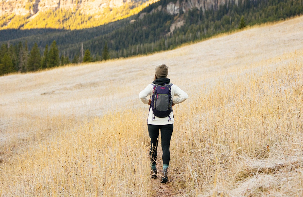 Woman hiking through a mountain meadow in the Oboz Sawtooth hiking boot.