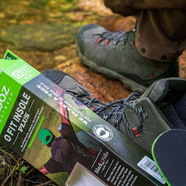 Oboz Black Folks Camp Too insole box near a creek bed.