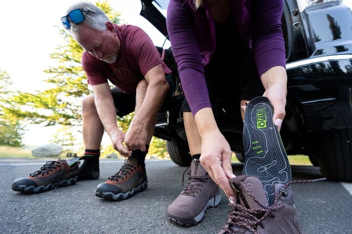 A couple gets ready for a hike by putting their Oboz O FIT insoles into their hiking shoes.