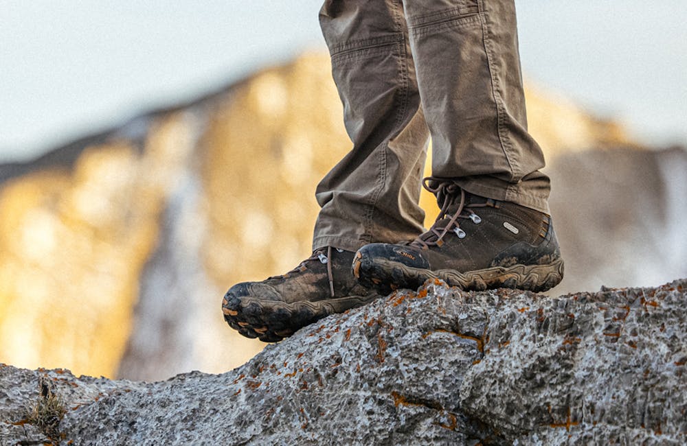 Hiker on a rock outcropping in Oboz Bridger mid hiking boots.