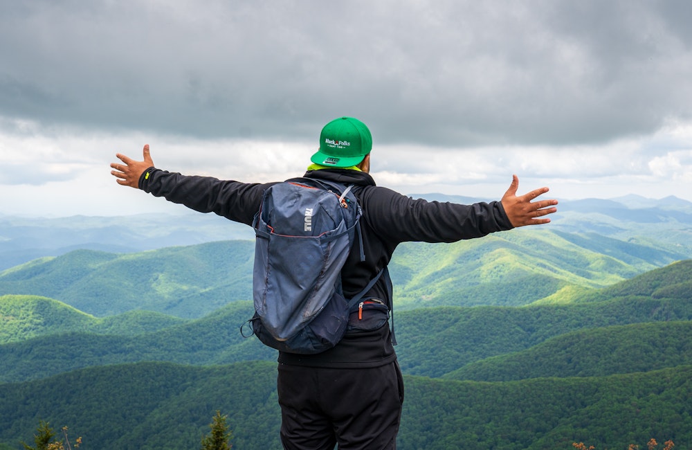 Hiker spreading their arms out a mountain top view point